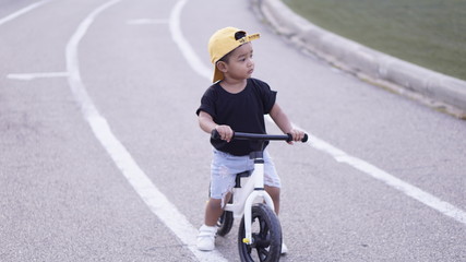 Cute little Asian 2 years old baby boy child learning to ride first balance bike kid playing & cycling at  Stadium Explore & Appreciate Nature with toddlers, First experience concept.