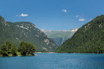 View of Swiss lake with blue waters, mountain hills with dense coniferous forests and crystal blue sky in the background, Sufnersee lake, Switzerland.