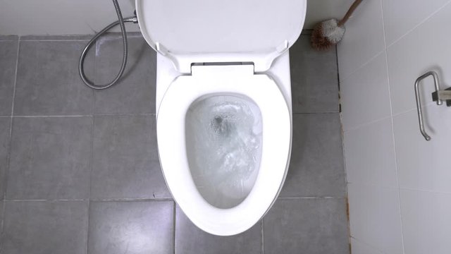 top view of Toilet Flushed. a water flushing down into the toilet bowl in bathroom. Slow motion shot of water being flushed in a toilet bowl.