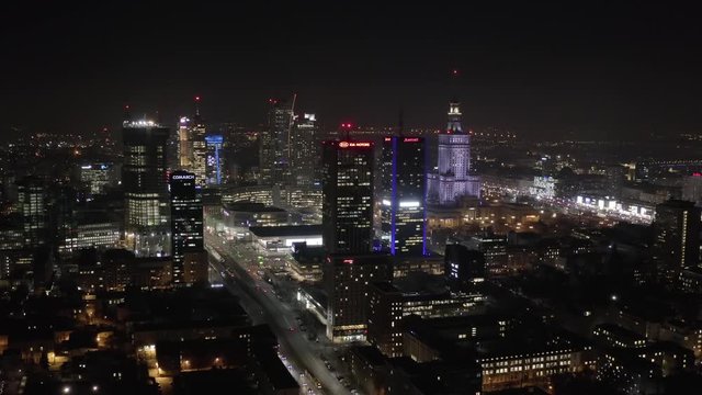 Aerial view of skyscrapers at dusk and city traffic in the center of Warsaw. Poland. 06. January. 2020. Drone flies towards the glass skyscrapers at night. 4K Shot.