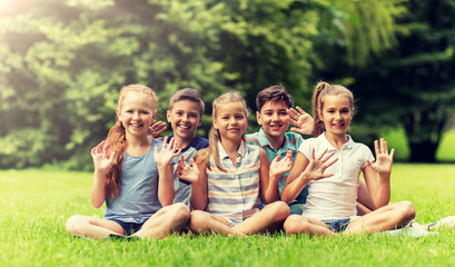friendship, childhood, leisure and people concept - group of happy kids or friends waving hands in summer park