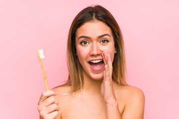 Young caucasian woman holding a teeth brush isolated shouting excited to front.