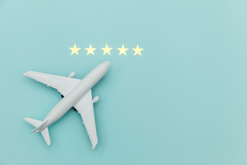 Fototapeta na wymiar Simply flat lay design miniature toy model plane and 5 stars rating on blue pastel colorful trendy background. Travel by plane vacation summer weekend sea adventure trip journey ticket tour concept.