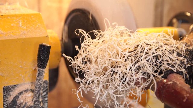 Craftsman works with workpiece in authentic workshop. Woodworker handles wood by bench. Making beautiful wooden handmade dish. Creation of unusual plate. Carpenter cuts wood by graver in soft focus.