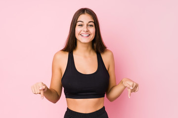 Young caucasian fitness woman doing sport isolated points down with fingers, positive feeling.
