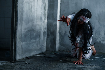  Halloween girl crawl on the ground with scary hands. Ghost women wear white dress stain blood at abandoned house