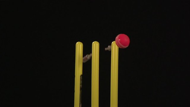 Flashing Cricket Bails bowled out - The stumps are hit with the pink ball. Black background. Super Slow motion