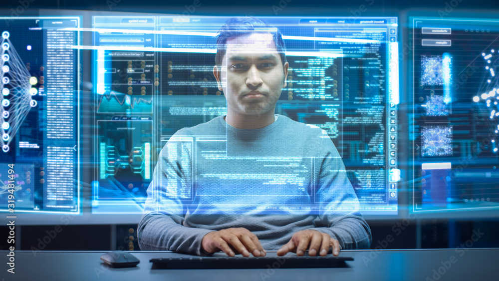 Poster Portrait of Software Developer / Hacker Wearing Glasses Sitting at His Desk and Working on Futuristic Transparent Computer in Digital Identity Cyber Security Data Center. Hacking or Programming.