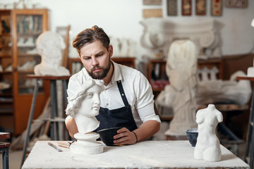Skillful sculptor makes professional restauration of gypsum sculpture of woman's head at the...