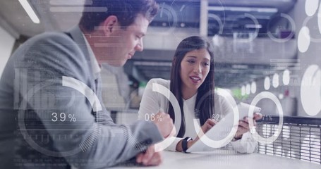 Digital composite of diverse business people in a meeting in office using digital tablet with graphics moving over the screen - Powered by Adobe