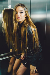 Portrait of sexy young caucasian woman fashion model posing in the modern elevator wearing black...