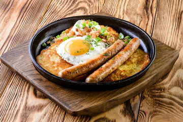 pan with fried egg, sausage and potato pancakes