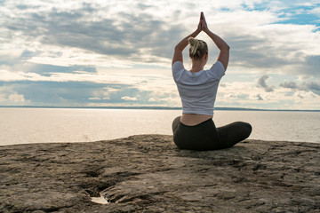 Fototapeta na wymiar Woman practicing Yoga, meditation or stretching close to water on Cliff doing different poses on beautiful landscape. Concept of finding ideal calm meditation place, finding yourself and Healthy Life.