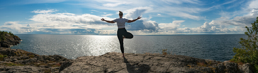Woman practicing Yoga, meditation or stretching close to water on Cliff doing different poses on...