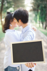 young romantic couple is kissing and the man holding blackboard for message. valentine concept, love concept