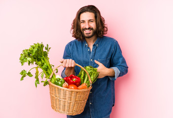 Young man picking organic vegetables from his garden isolated laughing and having fun.