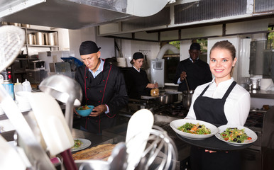 Waitress in restaurant kitchen with ordered meals