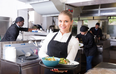 Waitress with dishes in kitchen