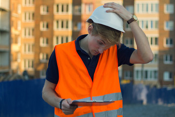 View of an Engineer and worker watching blueprint on construction site