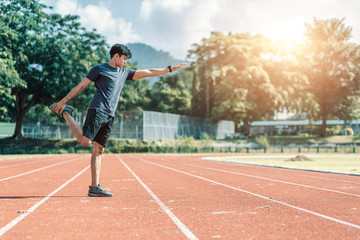 Full length portrait of a athletic man stretching at sport stadium.