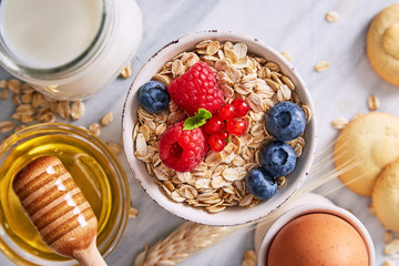 Oat meal healthy breakfast in a bowl with berrry fruits on a marble background. Top view