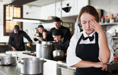 Tired and upset waitress in kitchen of restaurant