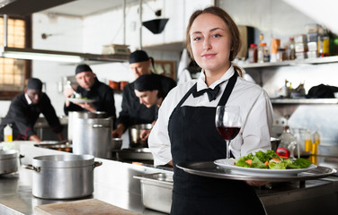 Professional waitress holding serving tray at restaurant kitchen