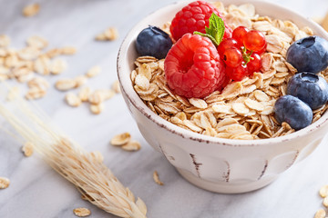 Oat meal healthy breakfast in a bowl with berrry fruits on a marble background. 