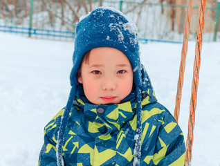 Cute Asian baby boy playing on snowfall white snow, sculpting snowballs with a toy snowball maker. Winter sport. We play in the Park in the fresh air. With a smile of happiness.