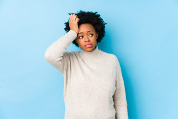 Middle aged african american woman against a blue background isolated being shocked, she has...