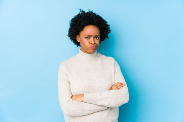 Middle aged african american woman against a blue background isolated unhappy looking in camera...