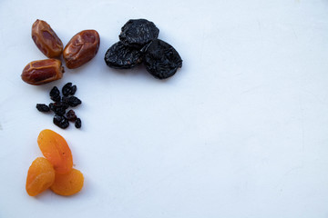 Different useful dried fruits on a white background. Prunes, dried apricots, dates and raisins. Appetizing picture for fruit lovers. Yummy.