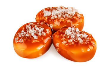 Sweet candies with salty caramel topping isolated  on white background. Toffee with caramel sauce macro