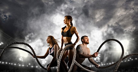 Sporty woman and man working out with battle ropes. Sports banner.