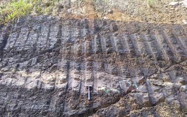 fractured volcanic rocks outcrop with burnd wood texture near the road