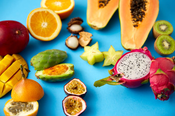food, summer and healthy eating concept - different exotic fruits on blue background