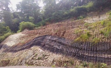 fractured volcanic rocks outcrop with burnd wood texture near the road
