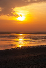 Naklejka premium France. Baie de Somme. Coucher de soleil sur l'océan et une plage de sable à marée basse. Sunset over the ocean and a sandy beach at low tide.