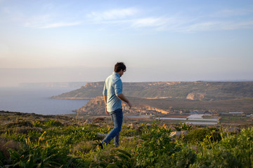 man walking in beautiful scenery watching an amazing view at the island Malta