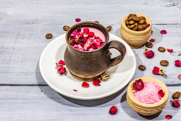 Trendy colored latte. Rose petals and powdered aromatic sugar, coffee beans. Wooden boards background