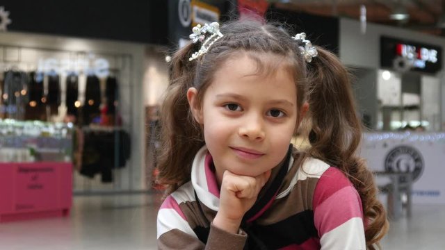 Cute little Girl with Pigtails Face Portrait, happy posing to a Camera in a Mall