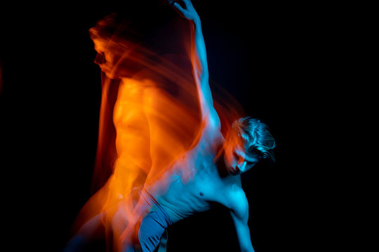handsome dancing man falls from his ghost reflection. mystical metaphorical portraits. game with the subconscious.  Blue and orange complementary colors. Creative long exposure photos series 