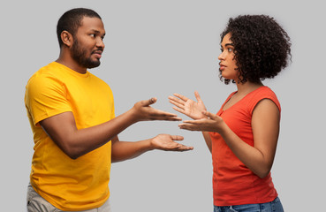relationships and people concept - unhappy african american couple having argument over grey...