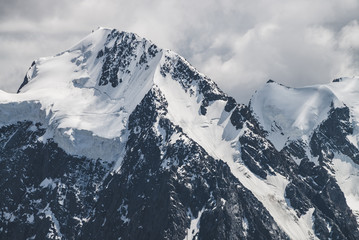 Atmospheric minimalist alpine landscape with massive hanging glacier on snowy mountain peak. Big balcony serac on glacial edge. Cloudy sky over snowbound mountains. Majestic scenery on high altitude.
