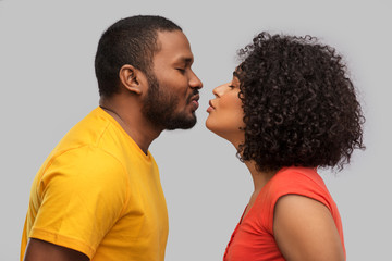 love, relationships and valentines day concept - happy african american couple reaching for kiss...