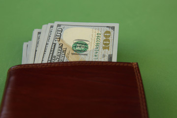 Wallet with a stack of one hundred dollars cash isolated on a green background. Business and...