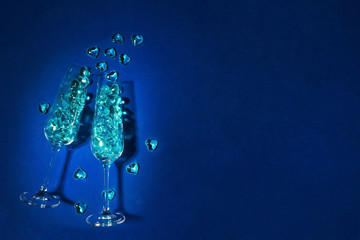 Festive classically blue background for a party, celebration. Champagne glasses filled with blue hearts. LGBT party concept