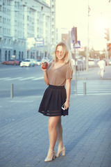 Outdoor fashion hipster style portrait of beautiful blonde woman drinking cocktail on the street