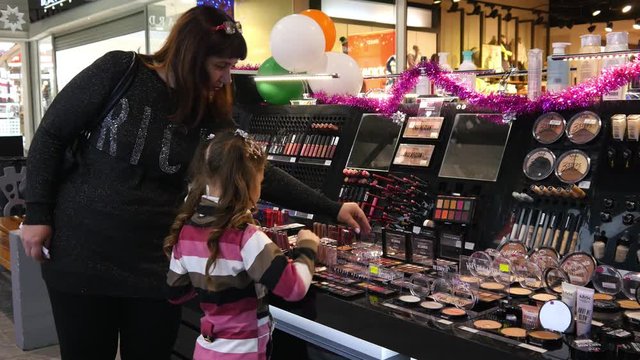 A Girl Kid chose cosmetics lipsticks, eye shadows in a Store