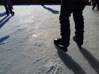 Feet with skates. Sports uniforms and equipment. Ice rink. Long shadows on ice from the low winter...